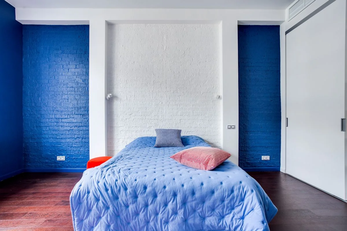 Navy blue accent wall behind a bed in a bedroom