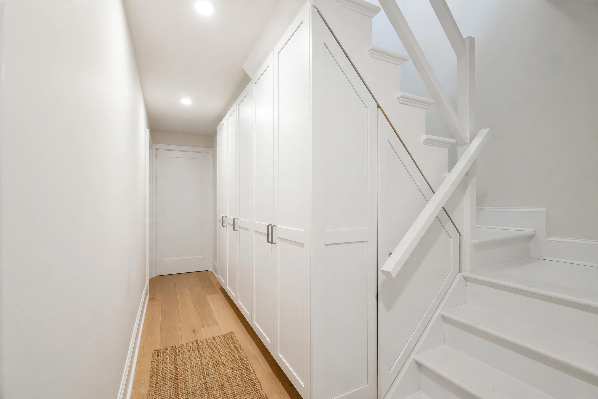 White under-stair cabinets brightening a small hallway