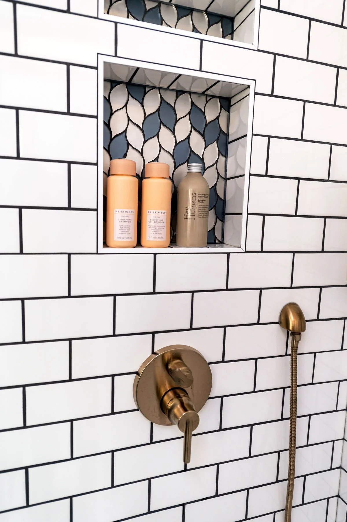 Built-in shower niche holding bottles in a tiled shower wall