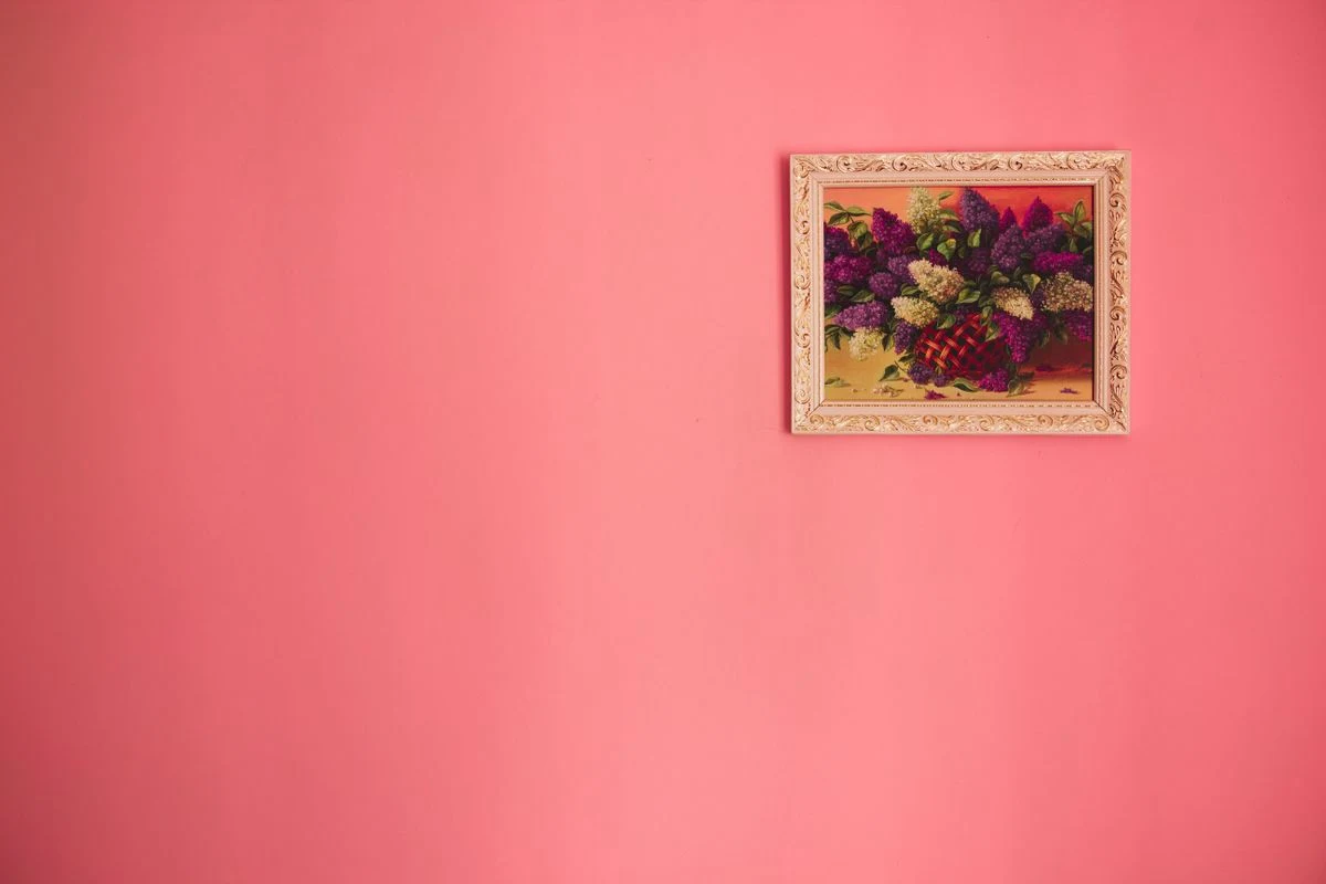 Pink wall art and framed prints above a bed