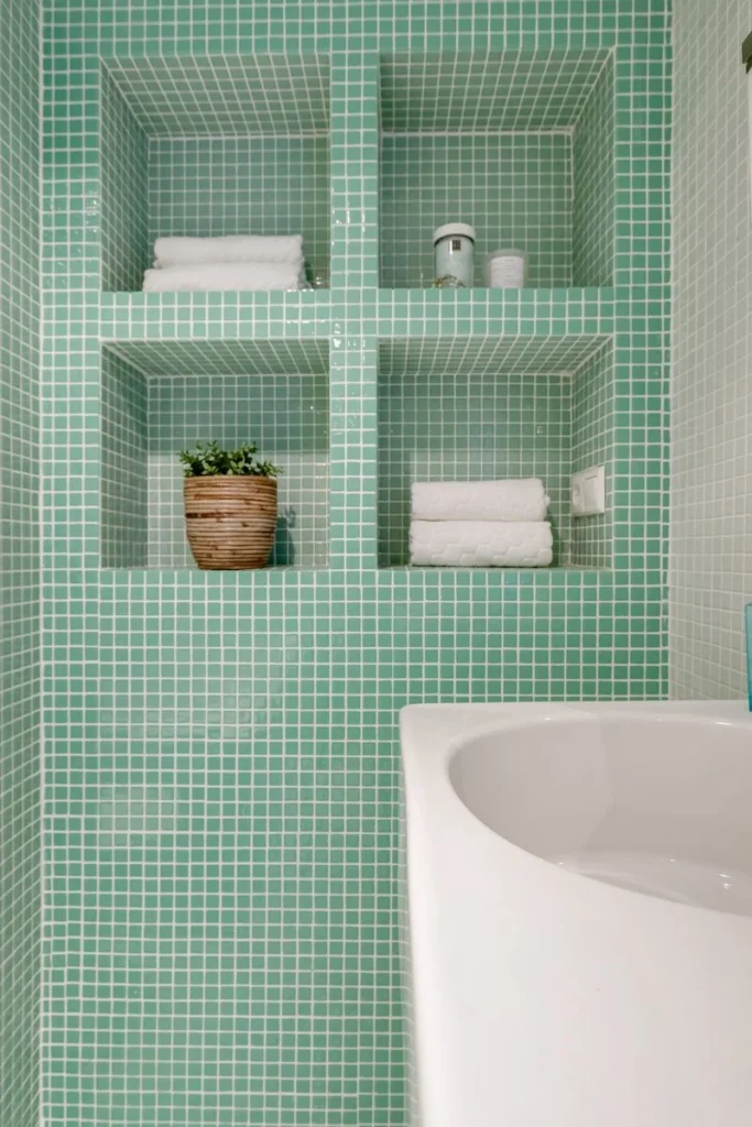 Recessed wall niche shelves with rolled towels beside a shower