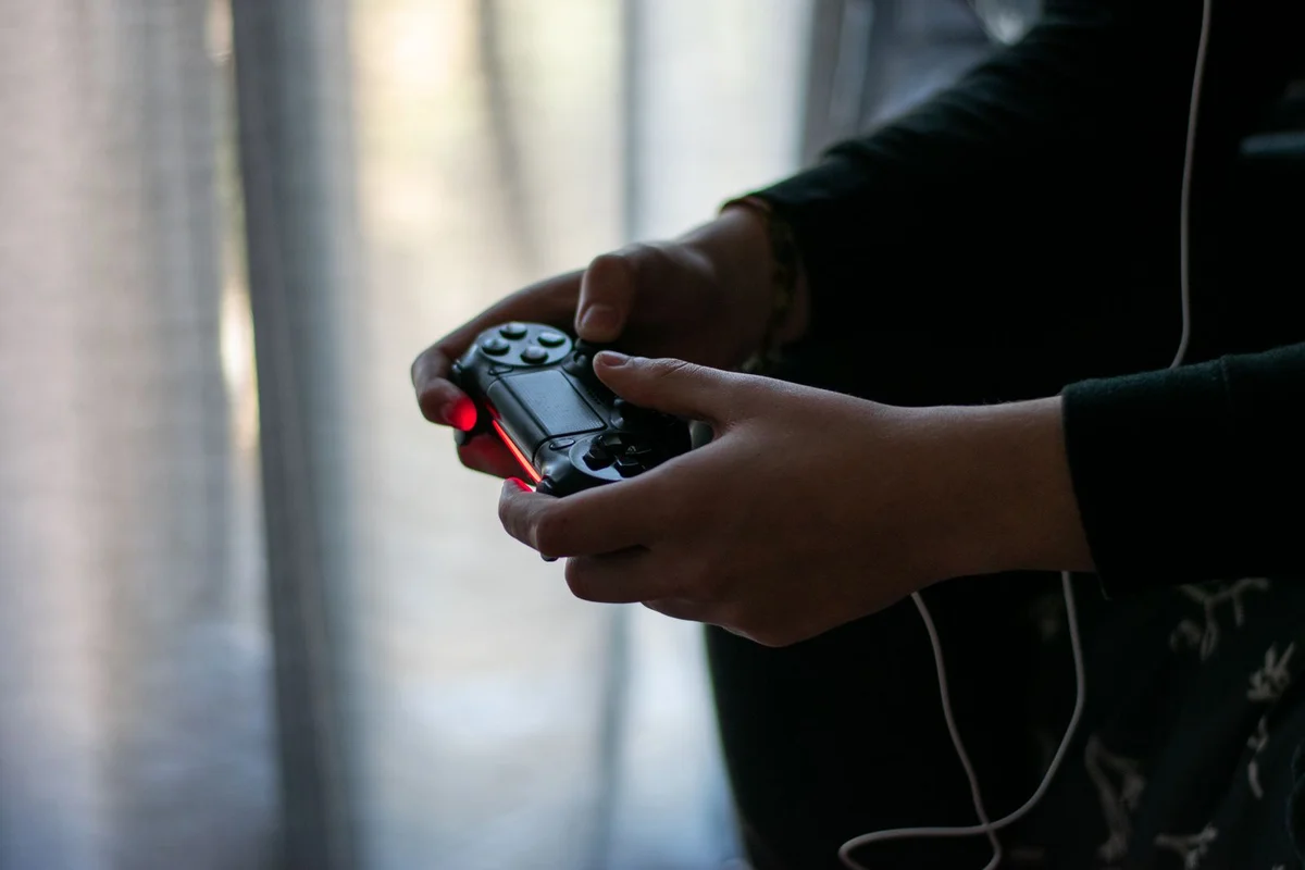 Close-up of hands gripping a video game controller in a dimly lit room
